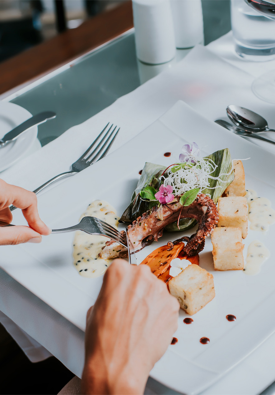 Weißer Teller mit Oktopus und gebratenem Mais, während einer Mahlzeit in einem Hotel der Pestana Hotels and Resorts