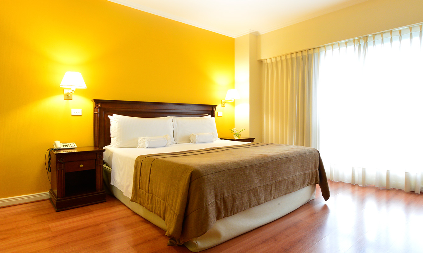 The Queen Deluxe Room at Pestana Buenos Aires has a double bed and a bedside table with a lamp