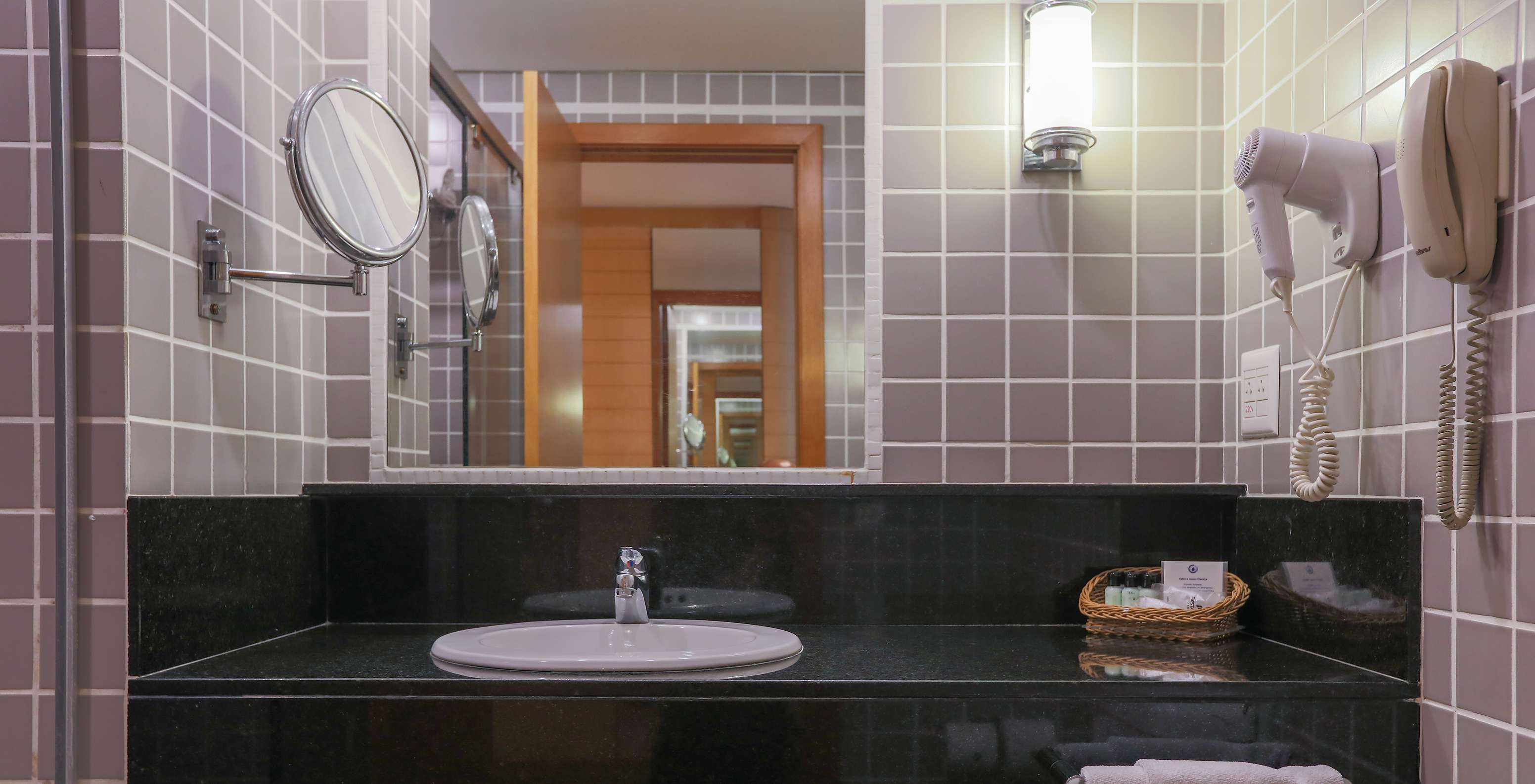 The Queen Standard at Pestana Curitiba has a bathroom with gray tiles and a black countertop with a sink