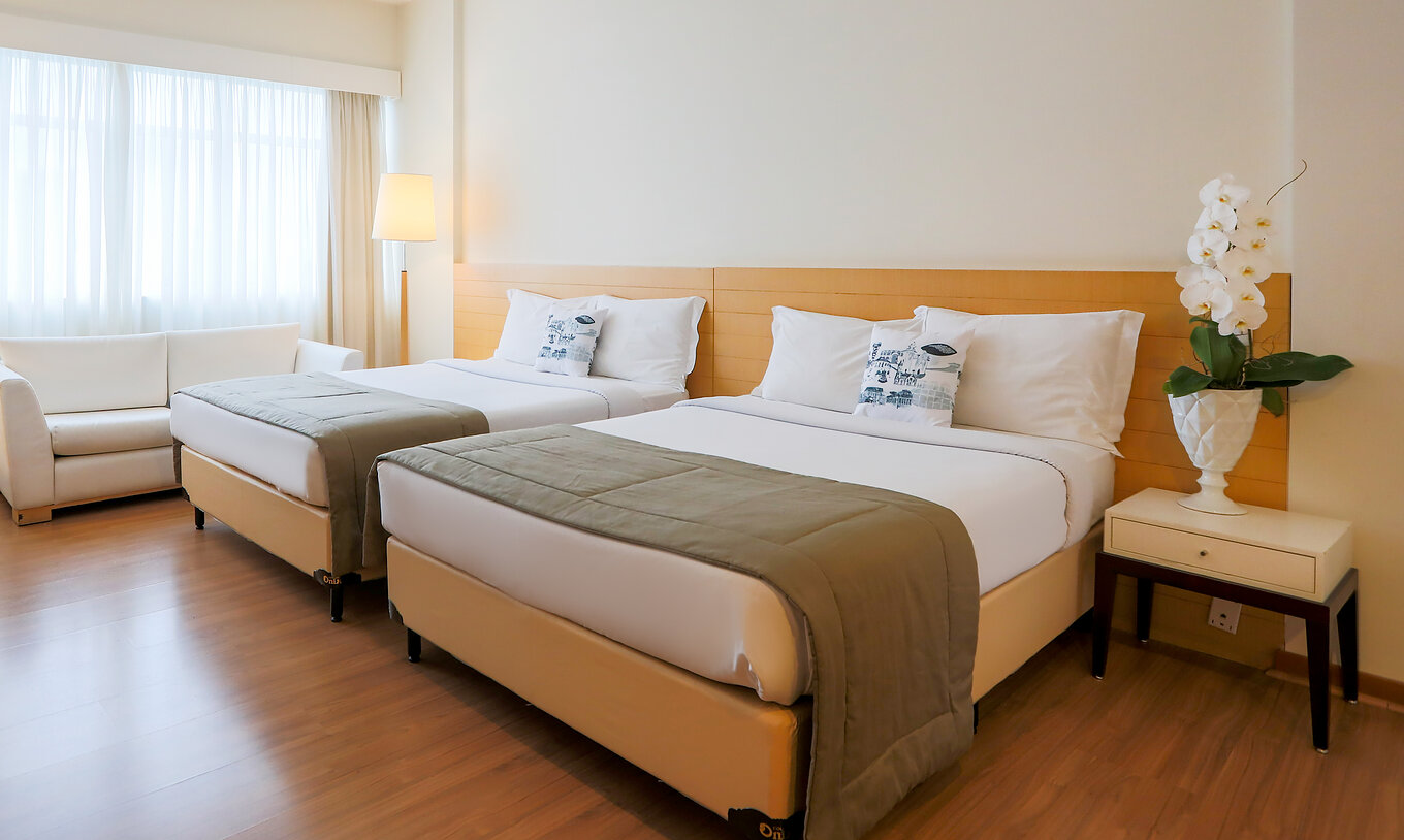 The Family Room at Pestana Curitiba has two double beds with a nightstand and a double sofa