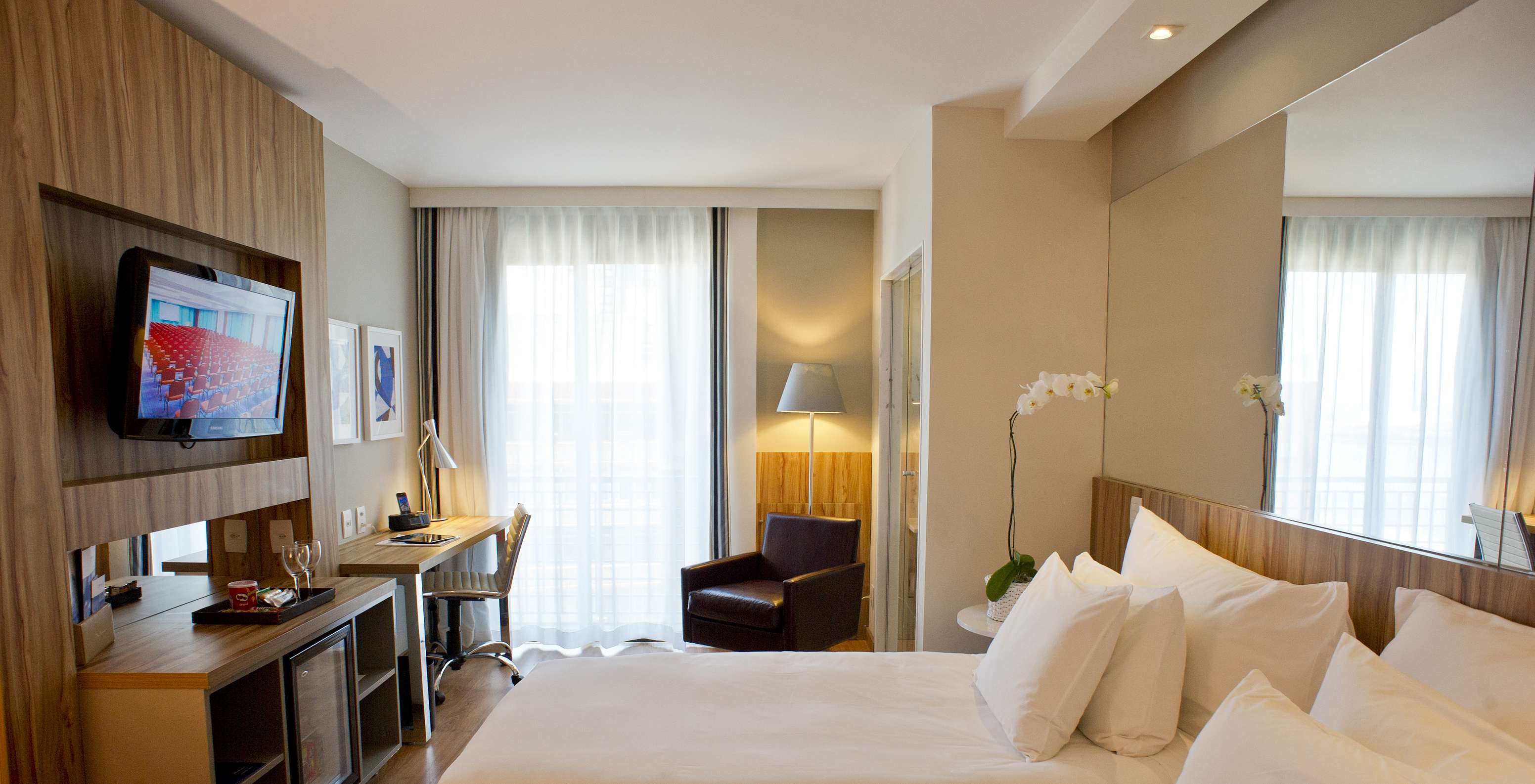 The Twin Standard of Pestana Rio Atlântica has two beds, mirror on the headboard, a television in front, and an armchair