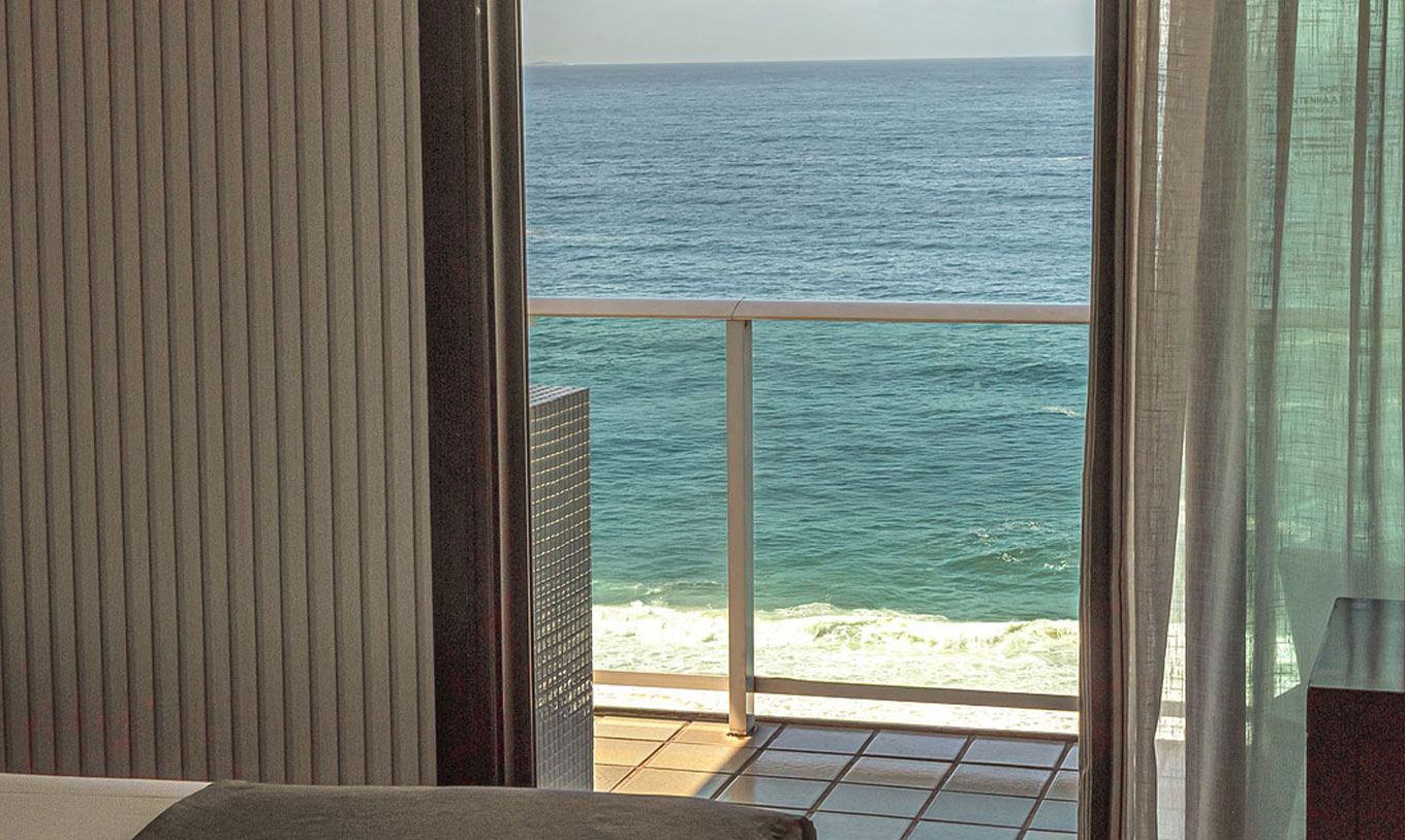 Suite Beach Front at Pestana Rio Atlântica with sea view balcony and open curtains from the room.