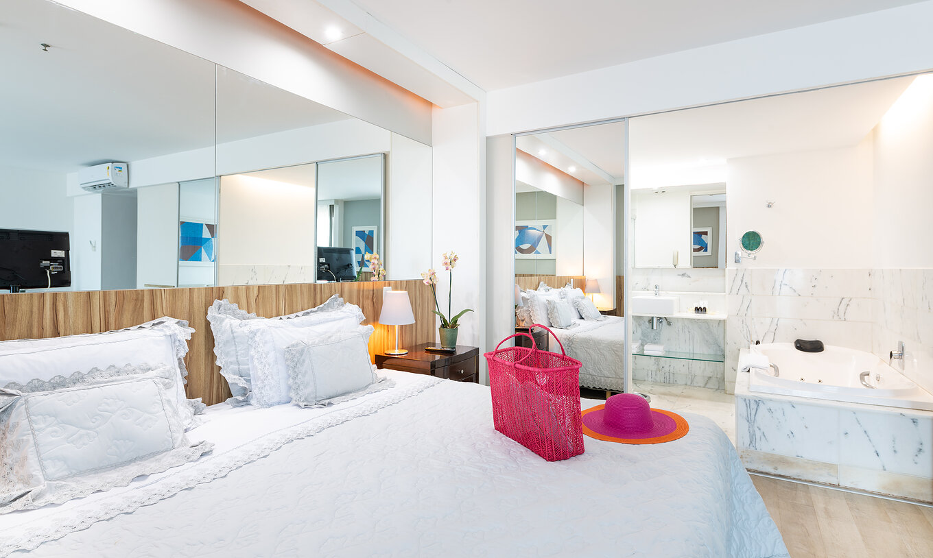 The Suite Junior Side Sea View of Pestana Rio Atlântica has a double bed, a mirror, and a bathroom with a bathtub