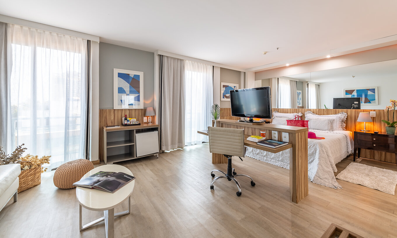 The Suite Junior Side Sea View of Pestana Rio Atlântica has a double bed, desk, television, and two windows with curtains