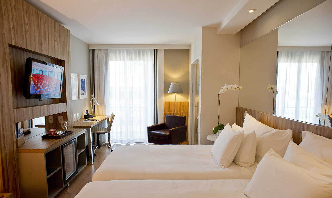 The Twin Standard of Pestana Rio Atlântica has two beds, mirror on the headboard, a television in front, and an armchair