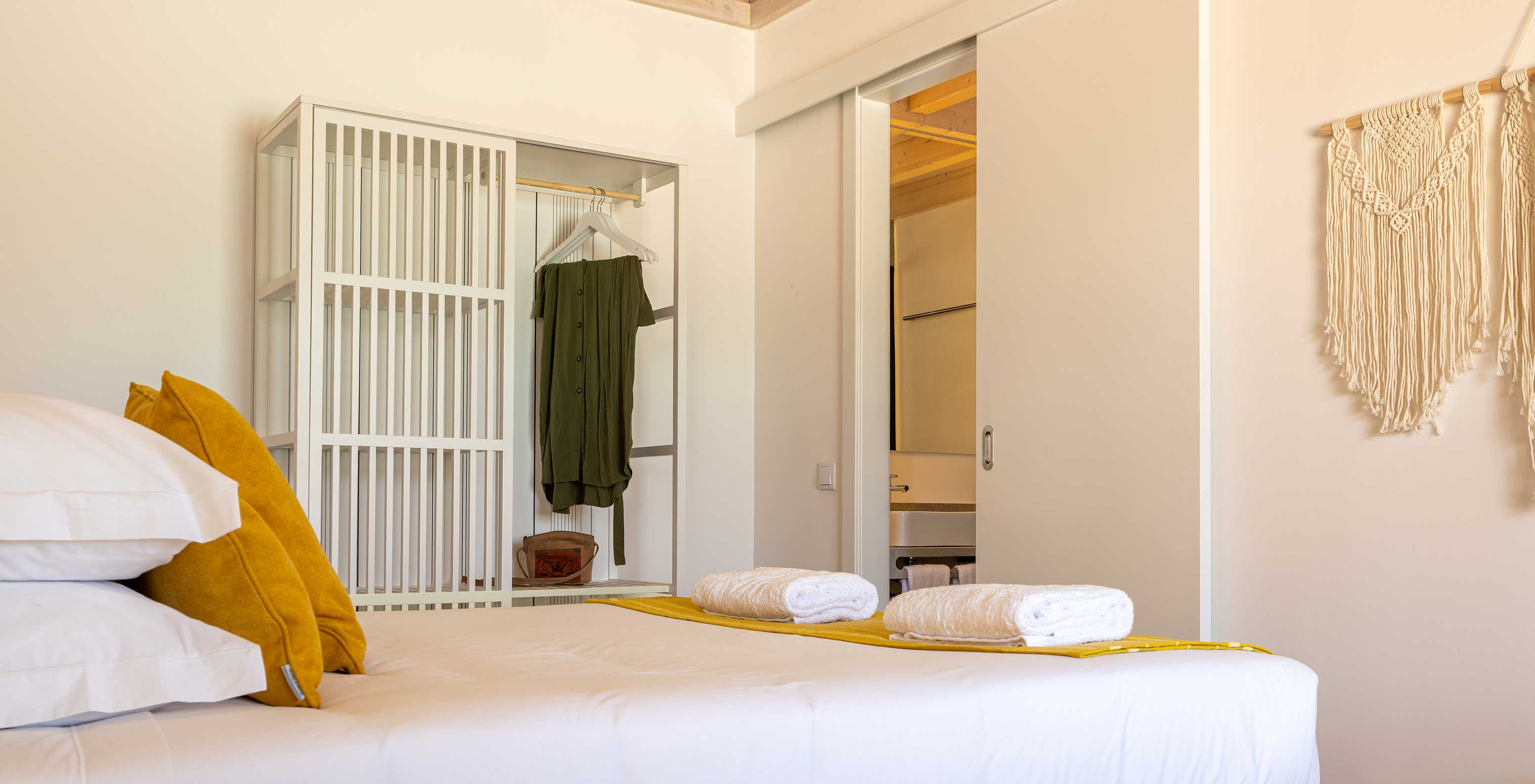 The Premium Villa at Pestana Comporta Village Residences has a minimalist bedroom with a bed and a bench