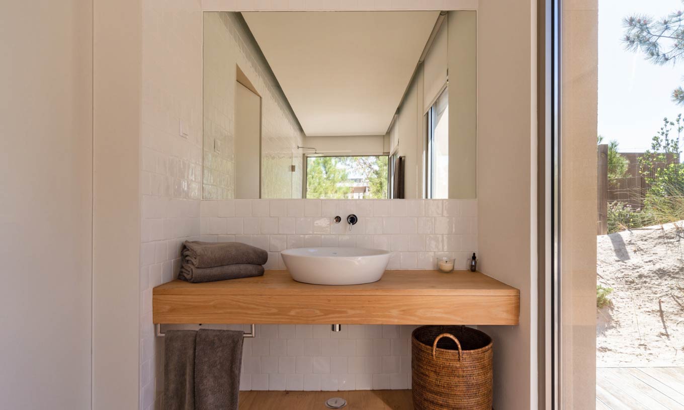 The exclusive villa with a pool at Pestana Tróia Eco Resort has a bathroom with a sink, a wooden counter, and a mirror