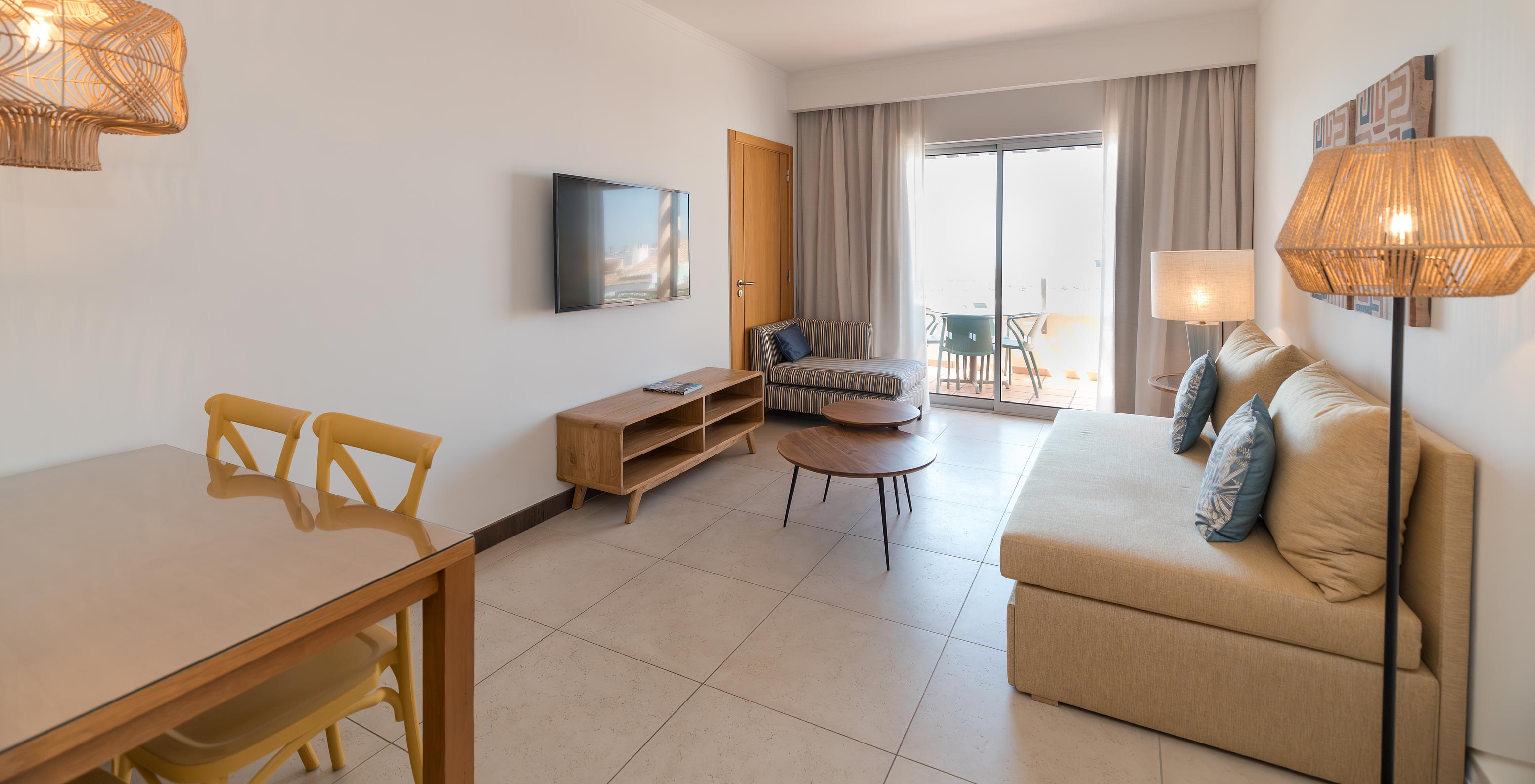 Apartment T1 Sea View at Pestana Alvor Beach Villas has a living room with sofa, TV and window with balcony access