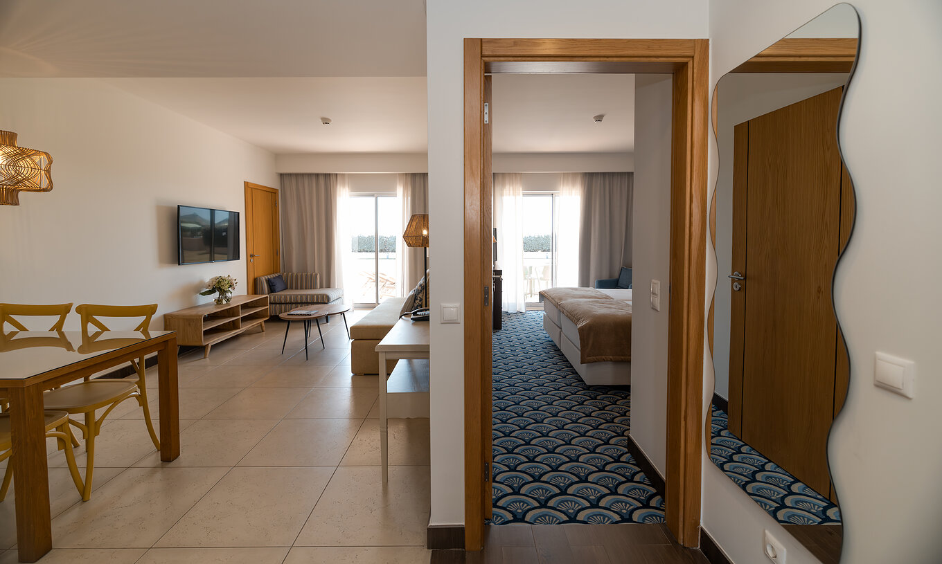 Apartment T1 Garden View at Pestana Alvor Beach Villas has a living room with sofa, TV and window with balcony