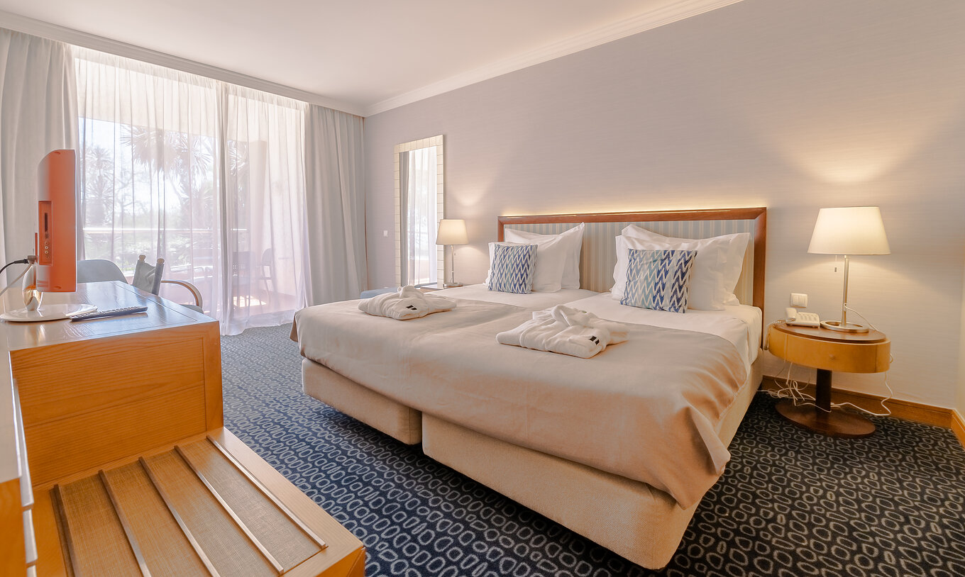 The T1 - with 1 Bedroom at Pestana Alvor Park has a double bed, blue carpet, and a desk with a television