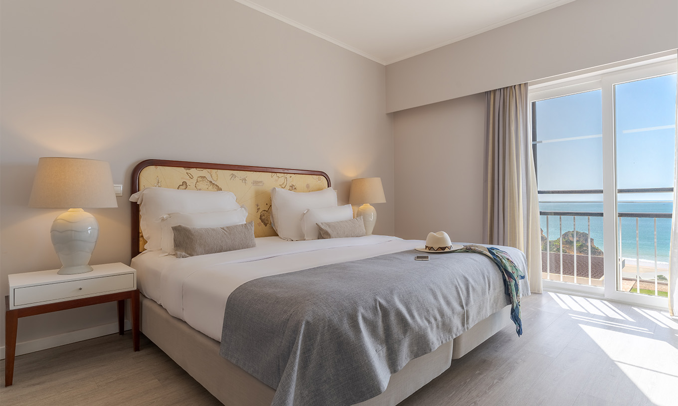 The Luxury Sea View Suite at Pestana Alvor Praia has a double bed, a bedside table with lamp, and sea views