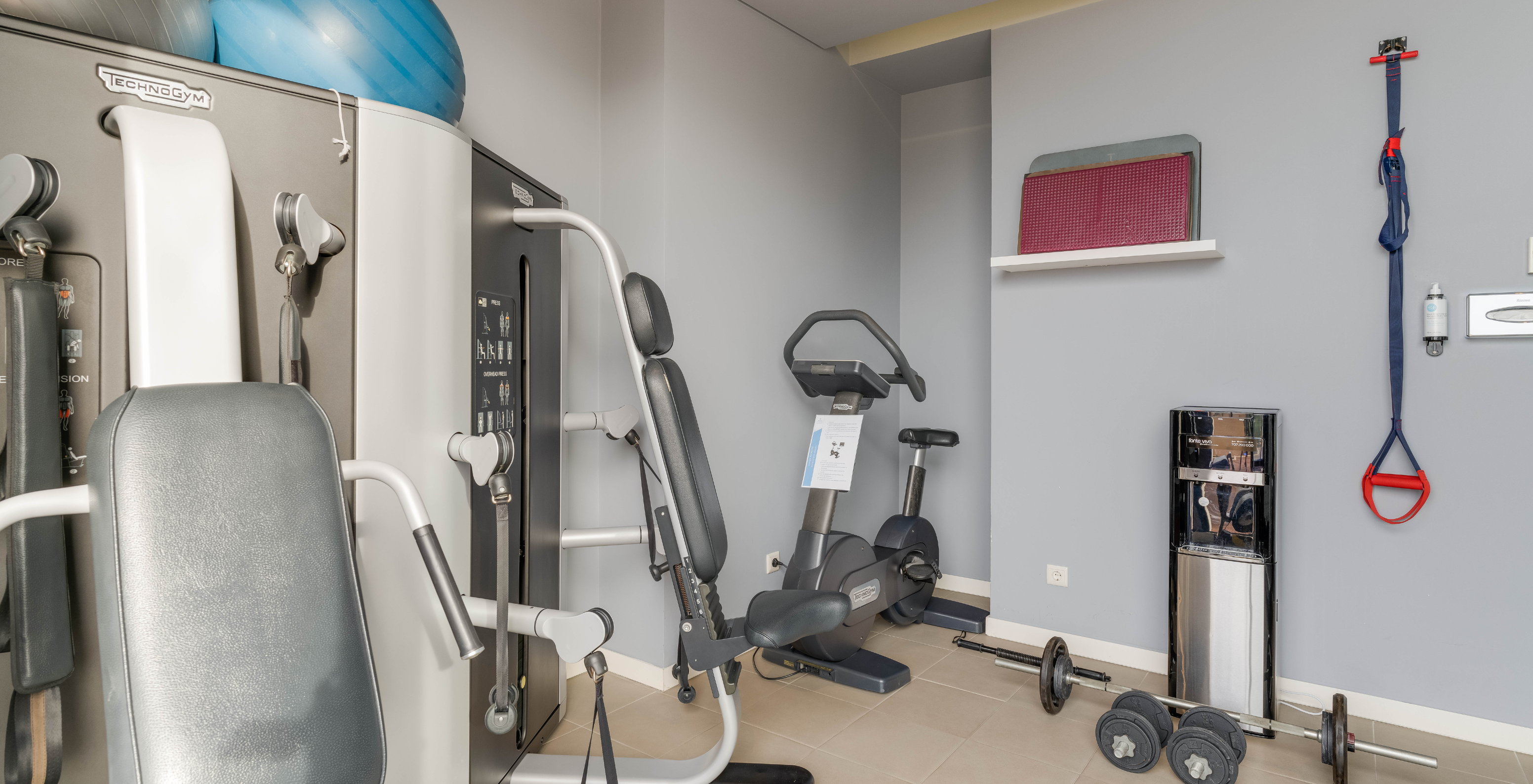 Four-star hotel gym on São Miguel Island with various machines and weights, available for guests