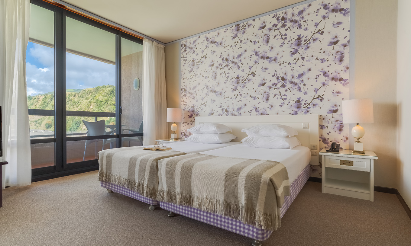 In Junior Sea View Suite at Pestana Bahia Praia, beds are next to the balcony, with views of gardens and sea