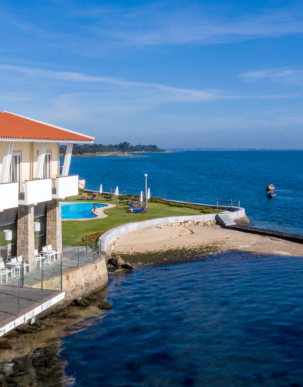 Facade of Pousada Ria in Aveiro, with a pool, leisure area, and direct access to the beach, facing a calm sea