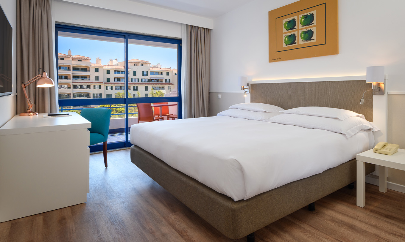 The Deluxe Suite at Pestana Cascais has a double bed, a desk, and a painted picture on the wall