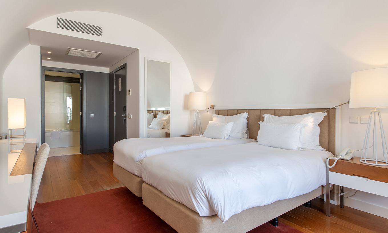 The Classic Room at Pestana Cidadela Cascais has two single beds, a red carpet, and a large mirror