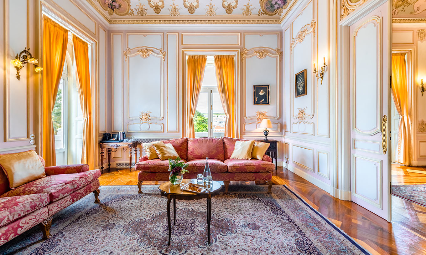 The Suite D. Carlos do Pestana Palace Lisboa has a large luxurious living room with two sofas, a rug and two windows