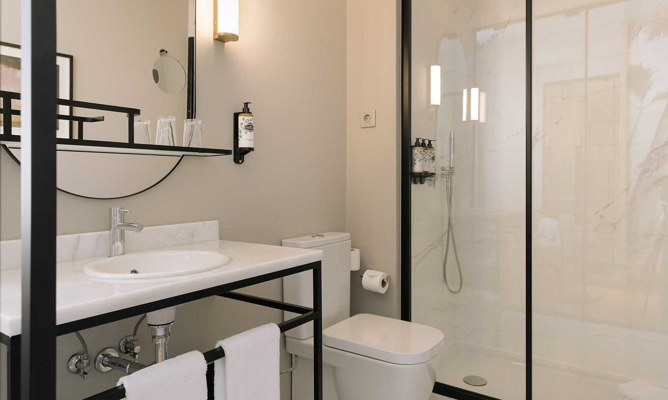 The Premium Corner of Pestana Rua Augusta Lisboa has a bathroom with sink with mirror, towels, toilet, and shower