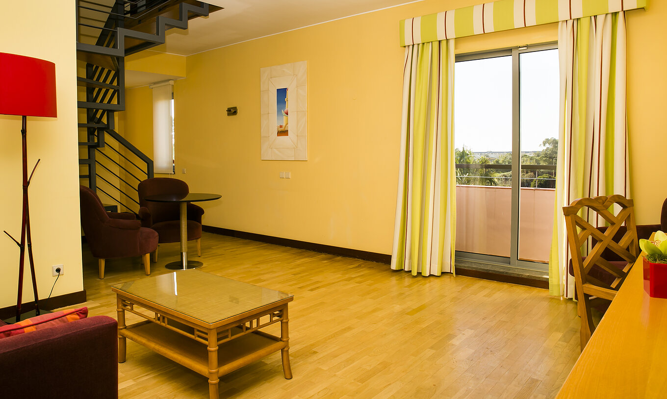 The Deluxe Mezzanine Suite of Pestana Sintra Golf has a room with armchairs, coffee table, and window with balcony access