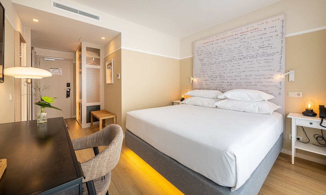 The Superior Room at Pestana Fisherman Village features a double bed with a headboard with written phrases and a desk