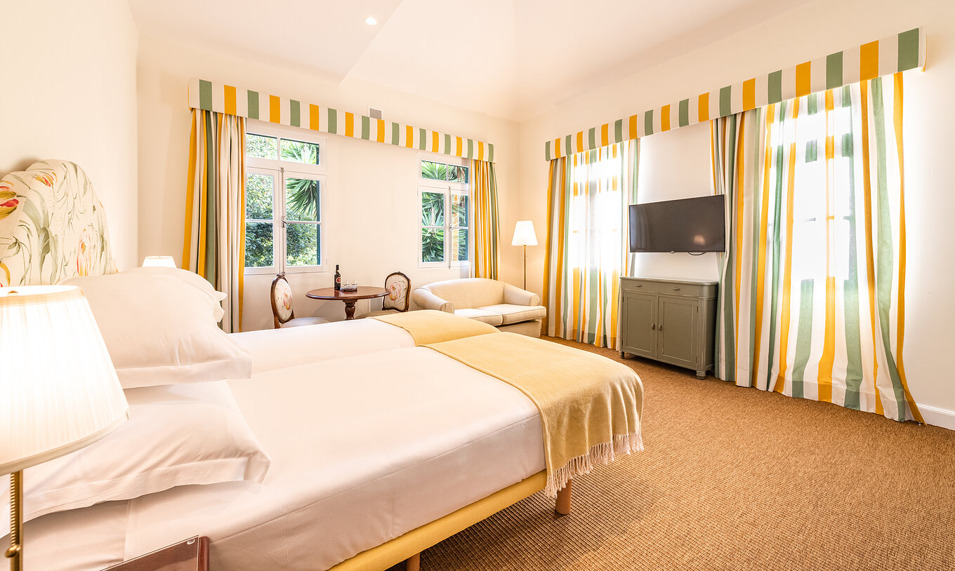 The Manor House - 1 of Pestana Quinta do Arco has two joined beds, sofa, table, television, carpet, and windows with curtains