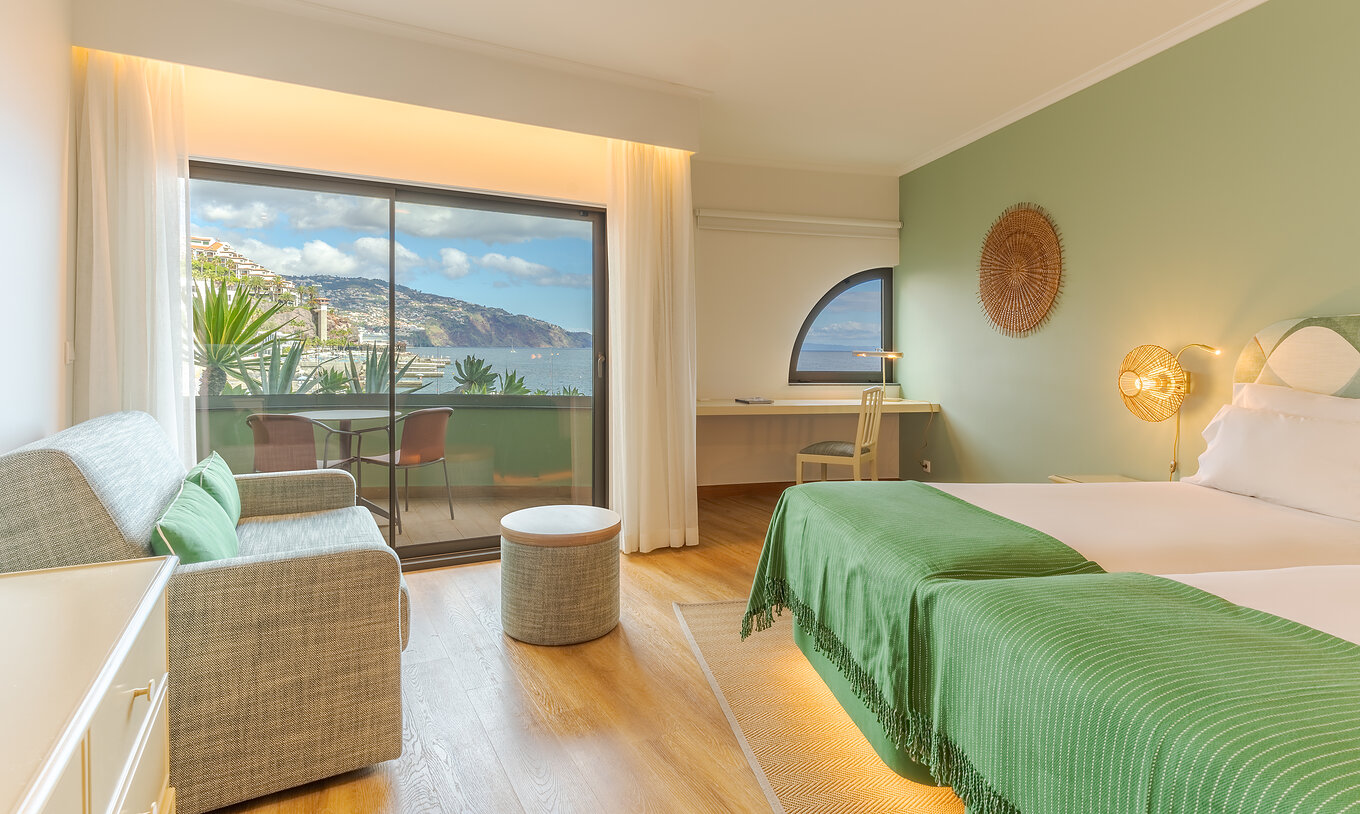 The Classic Lateral Sea View room at Pestana Vila Lido Madeira features a small window at the desk and a window with balcony