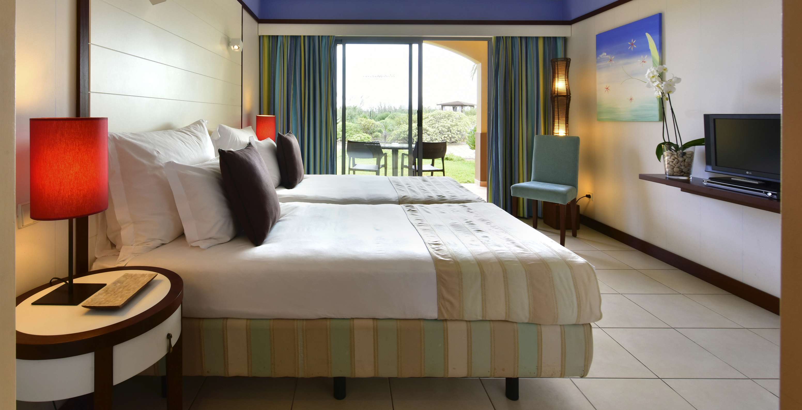 The Classic Double of Pestana Porto Santo All Inclusive has two beds, a chair, and a balcony with a table and garden view