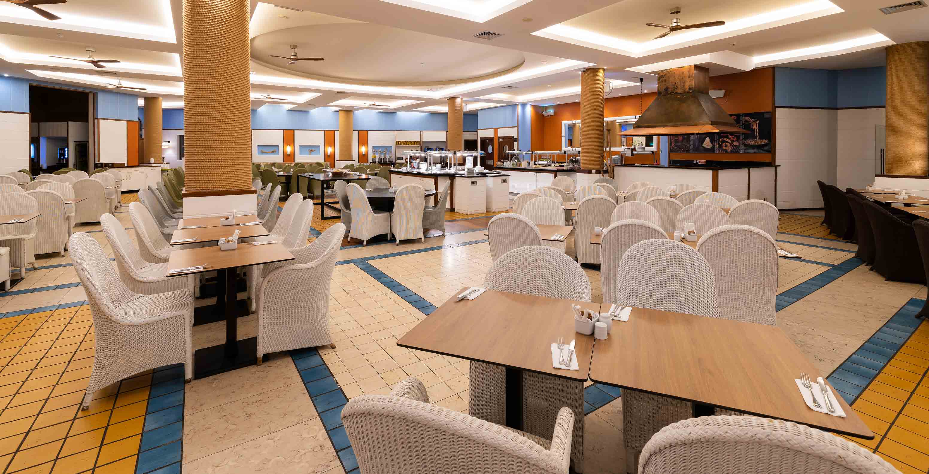 Spacious area of the Marés Restaurant at Pestana Porto Santo with blue and yellow details and white chairs