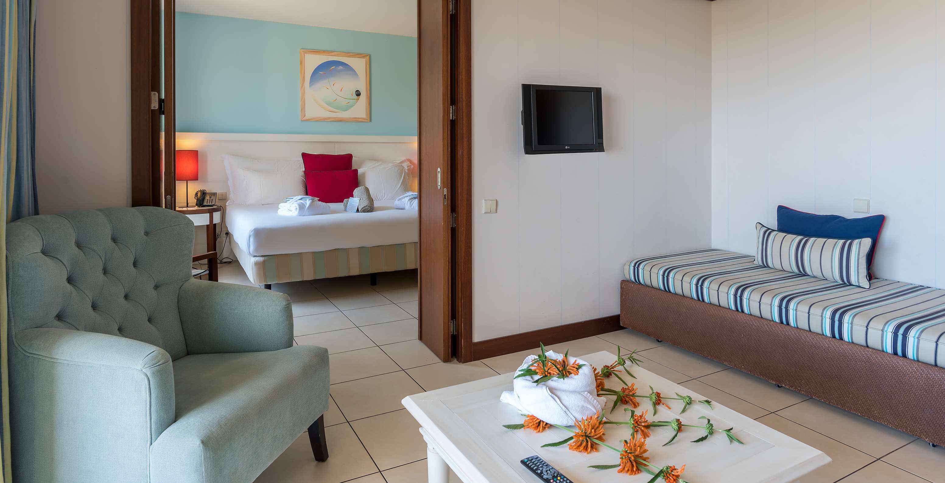 The T1 Suite Apartment of Pestana Porto Santo All Inclusive has a bedroom with a double bed and a living room with a sofa