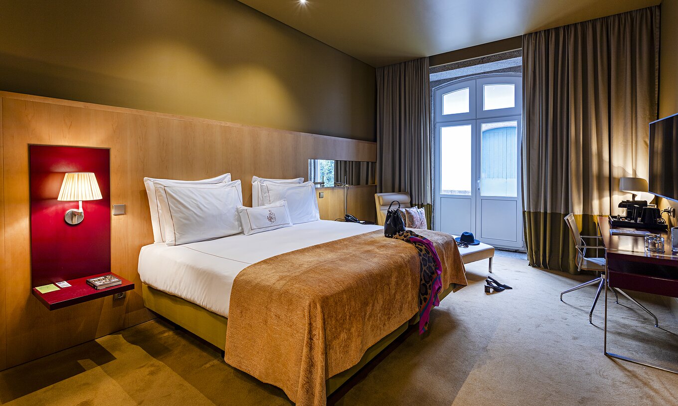 Pestana Palácio do Freixo’s Classic room has a large window, double bed, and a bedside table