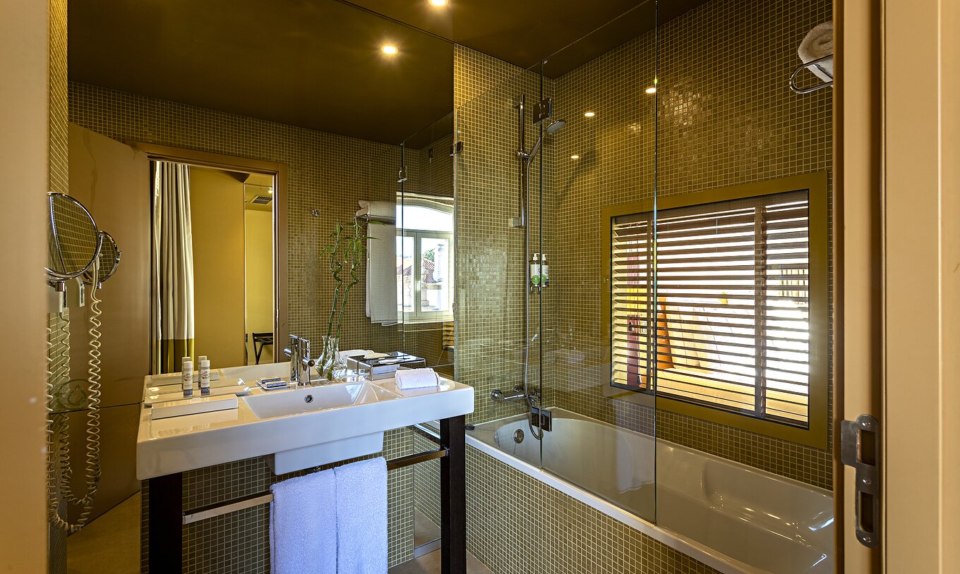 The Deluxe Grand View has a bathroom with a bathtub and a window to the bedroom