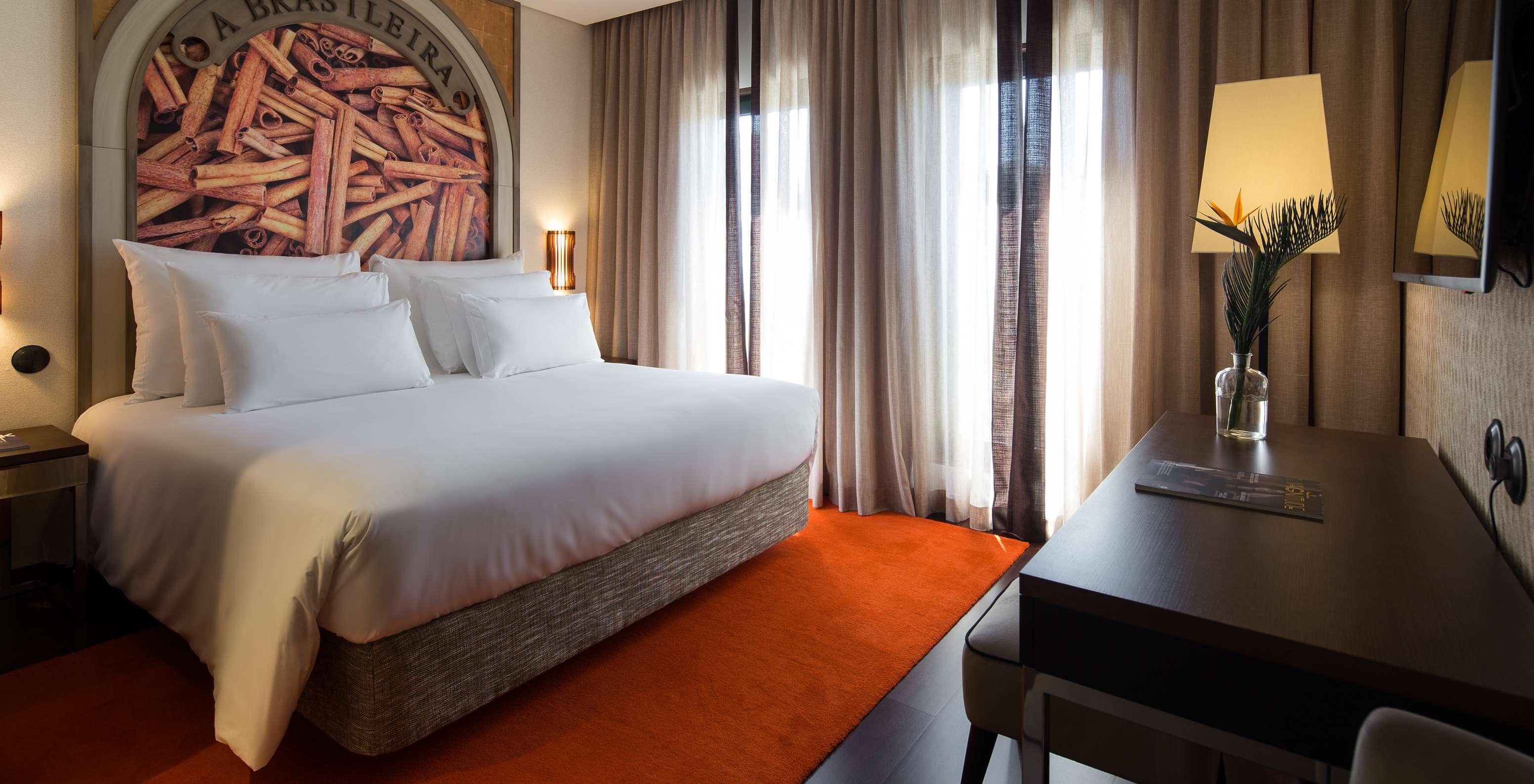 The Deluxe Executive Grand View do Pestana Porto - A Brasileira has a king size bed with a themed mural about cinnamon