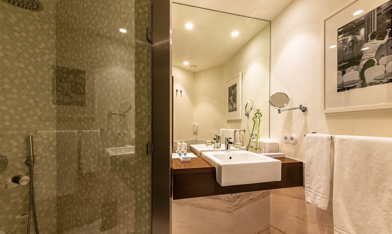 The Deluxe do Pestana Porto - A Brasileira has a bathroom with modern decoration, with sink, shower and a mirror