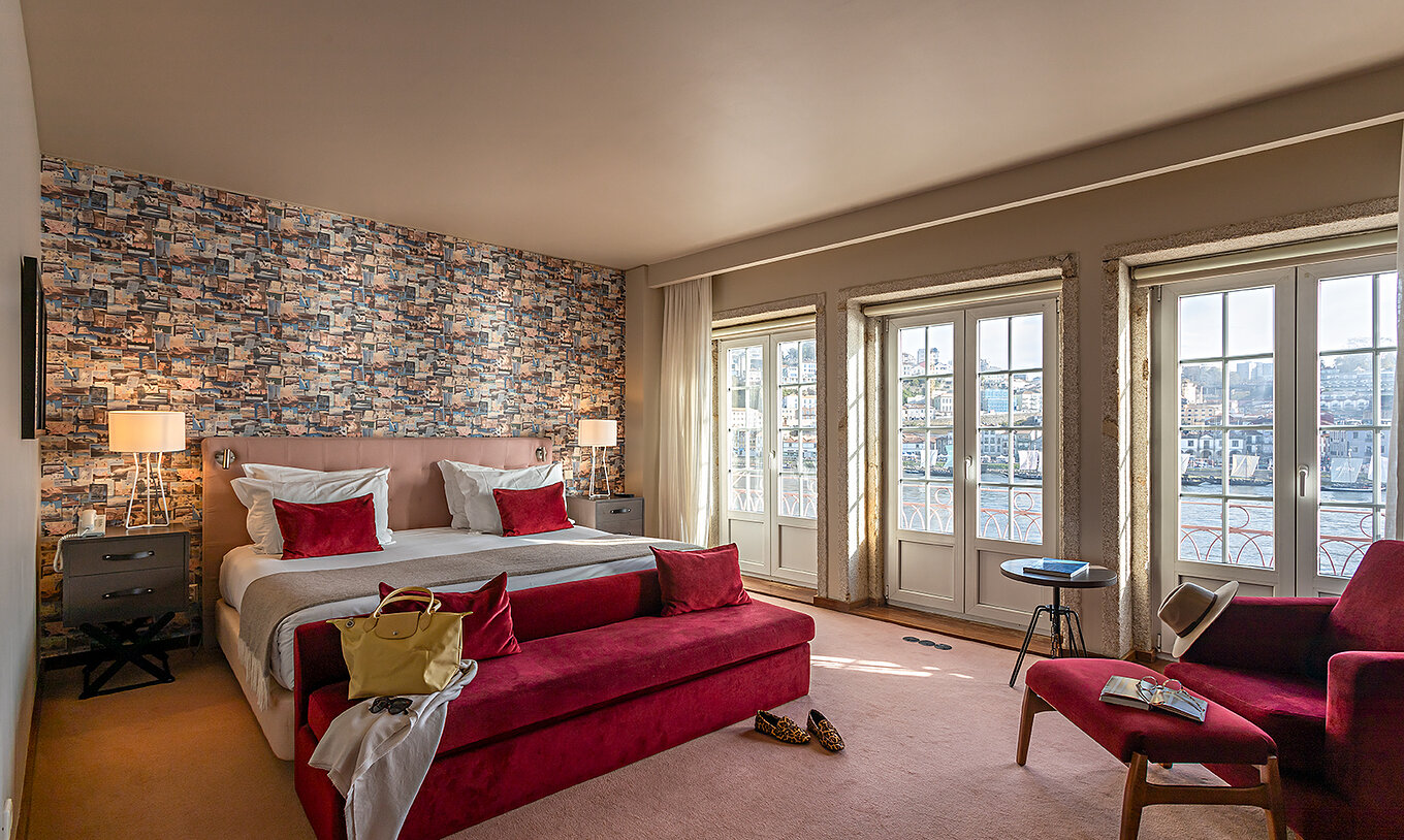 The Suite Grand View at Pestana Vintage Porto has a double bed, a red sofa and windows with a view of Porto