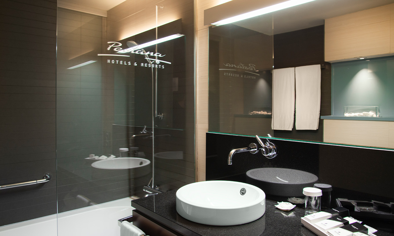 Deluxe room at Pestana Arena Barcelona has a bathroom with bathtub with shower and a sink with mirror