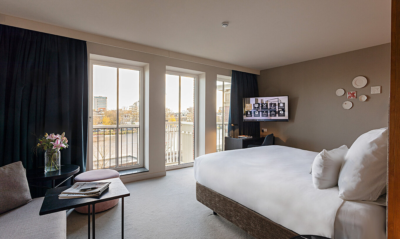 Premium - River View room at Pestana Amsterdam Riverside has large glass windows, with a view of the river, and a table