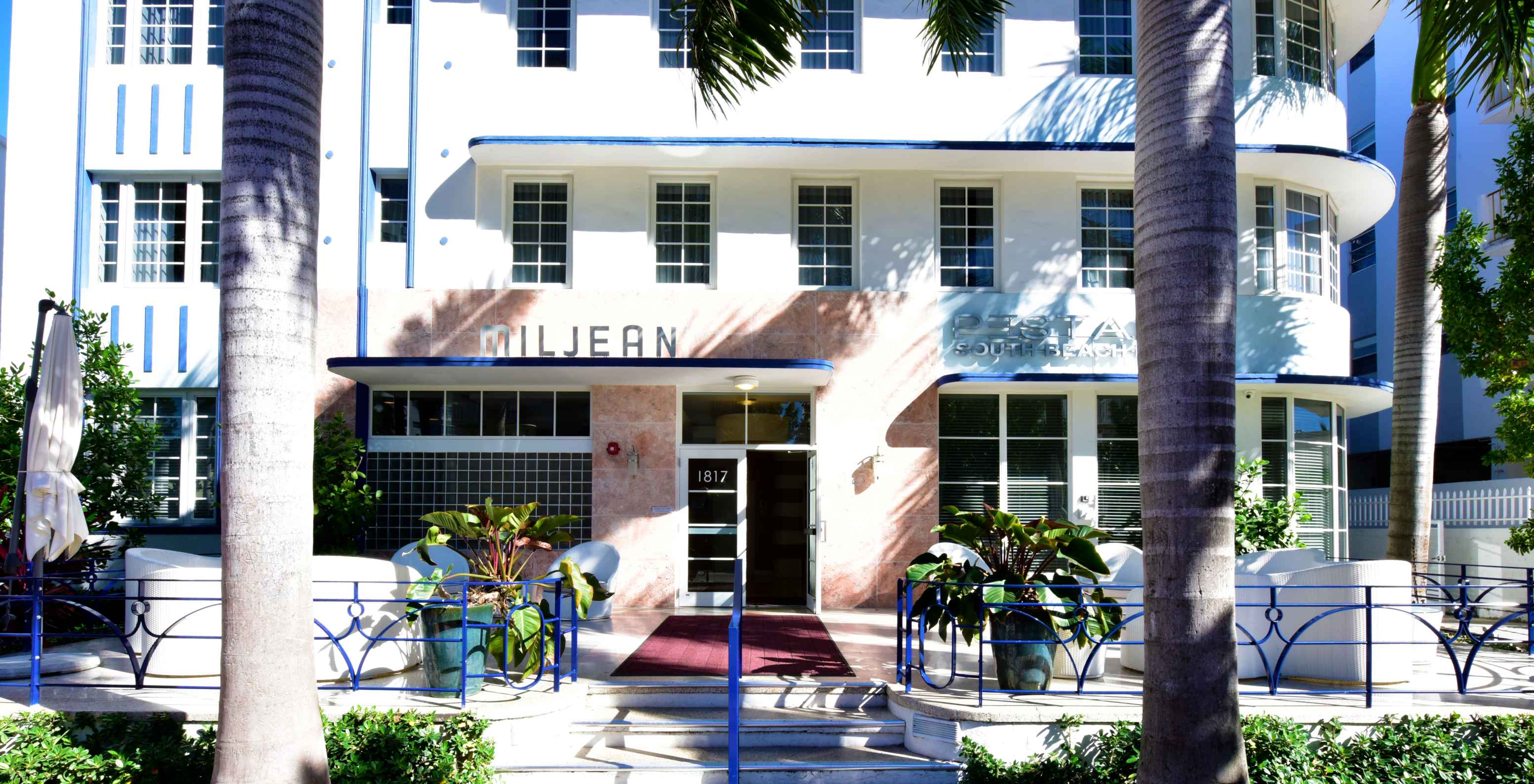 View of the entrance of Pestana Miami South Beach with chairs, tables, and the hotel facade in the background