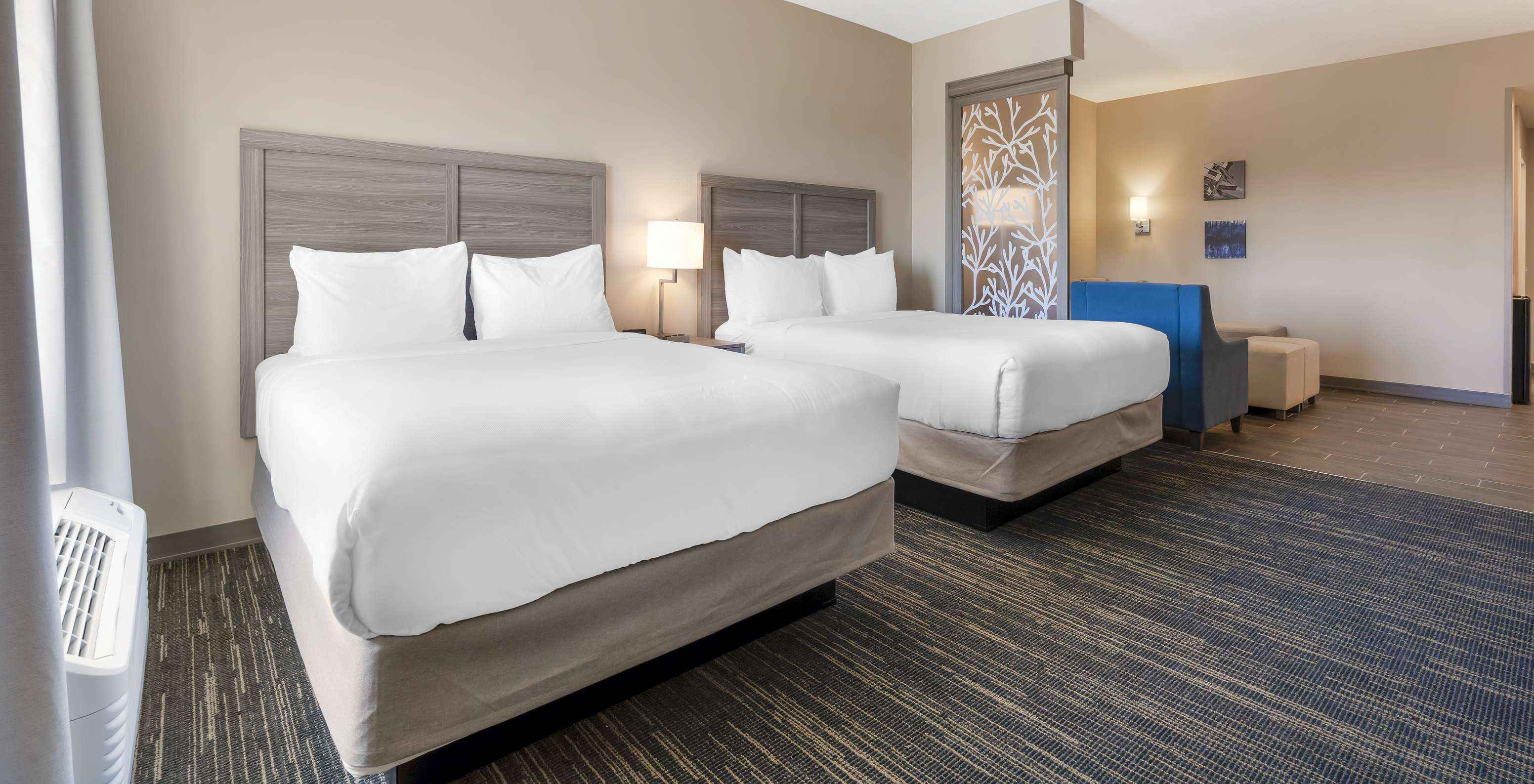The Master Double Queen Suite at Pestana Orlando Suites Lake Buena Vista has two beds and a bedside table with a lamp