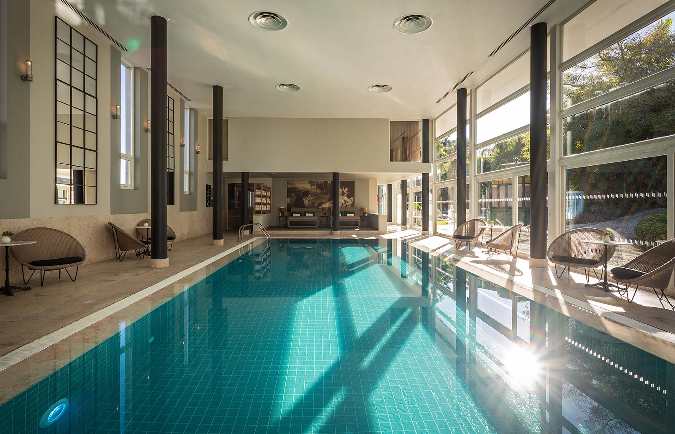 Indoor pool at Pestana Palace Spa, with natural light streaming through the windows and relaxation areas in the background