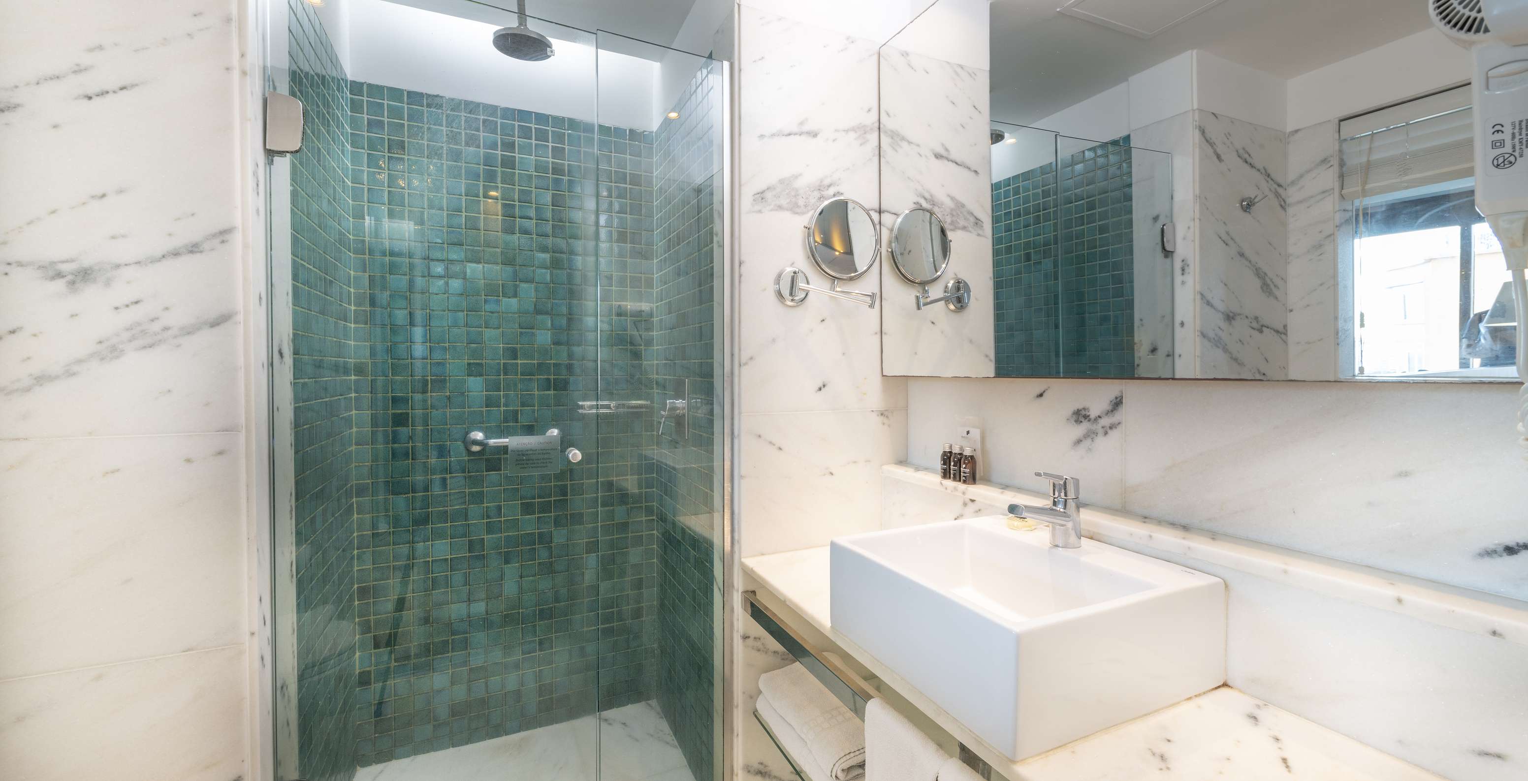 The Queen Standard of Pestana Rio Atlântica has a bathroom with shower, sink with mirror, and magnifying mirror