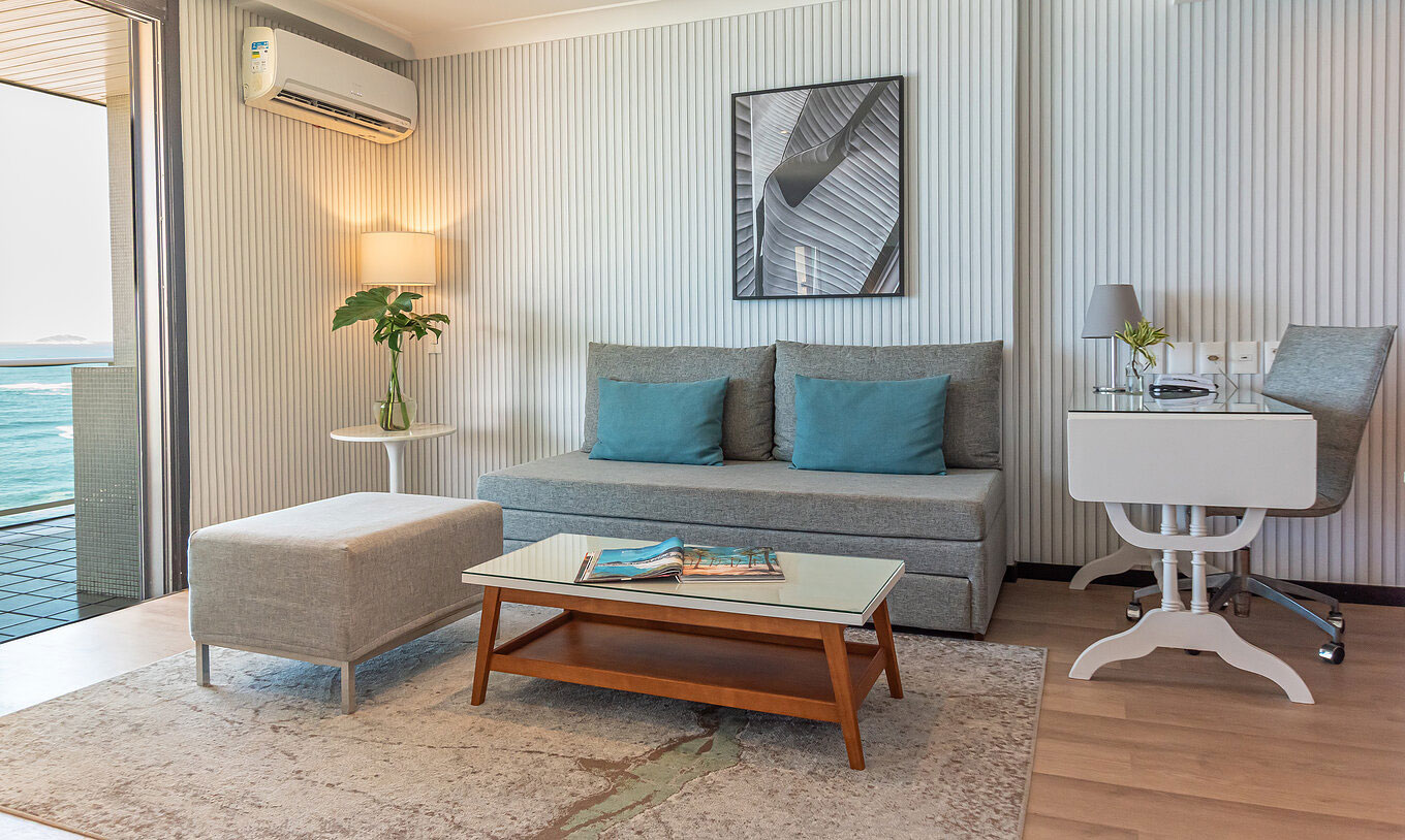 The Suite Beach Front at Pestana Rio Atlântica has a modern lounge with sofa, desk, table and sea view.