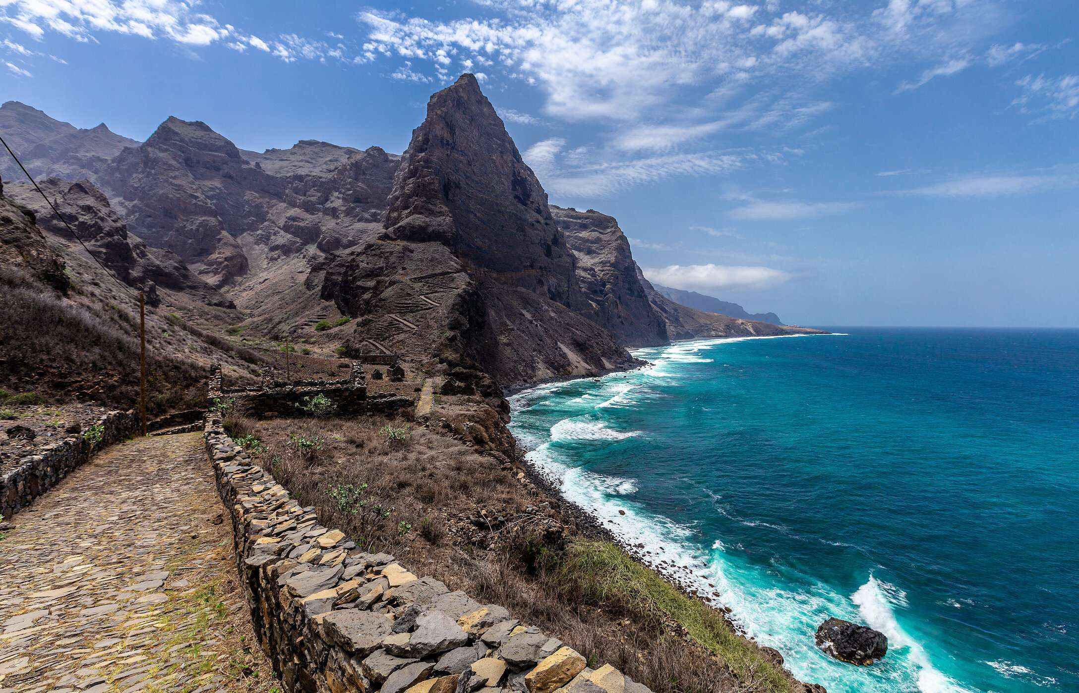 Stone trail winds along the coast with a steep cliff on Santo Antão Island, Cape Verde