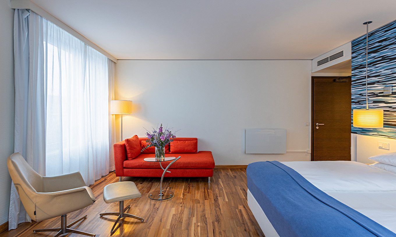 Grand Deluxe room at Pestana Berlin Tiergarten has a double bed, a sofa, coffee table, and an armchair