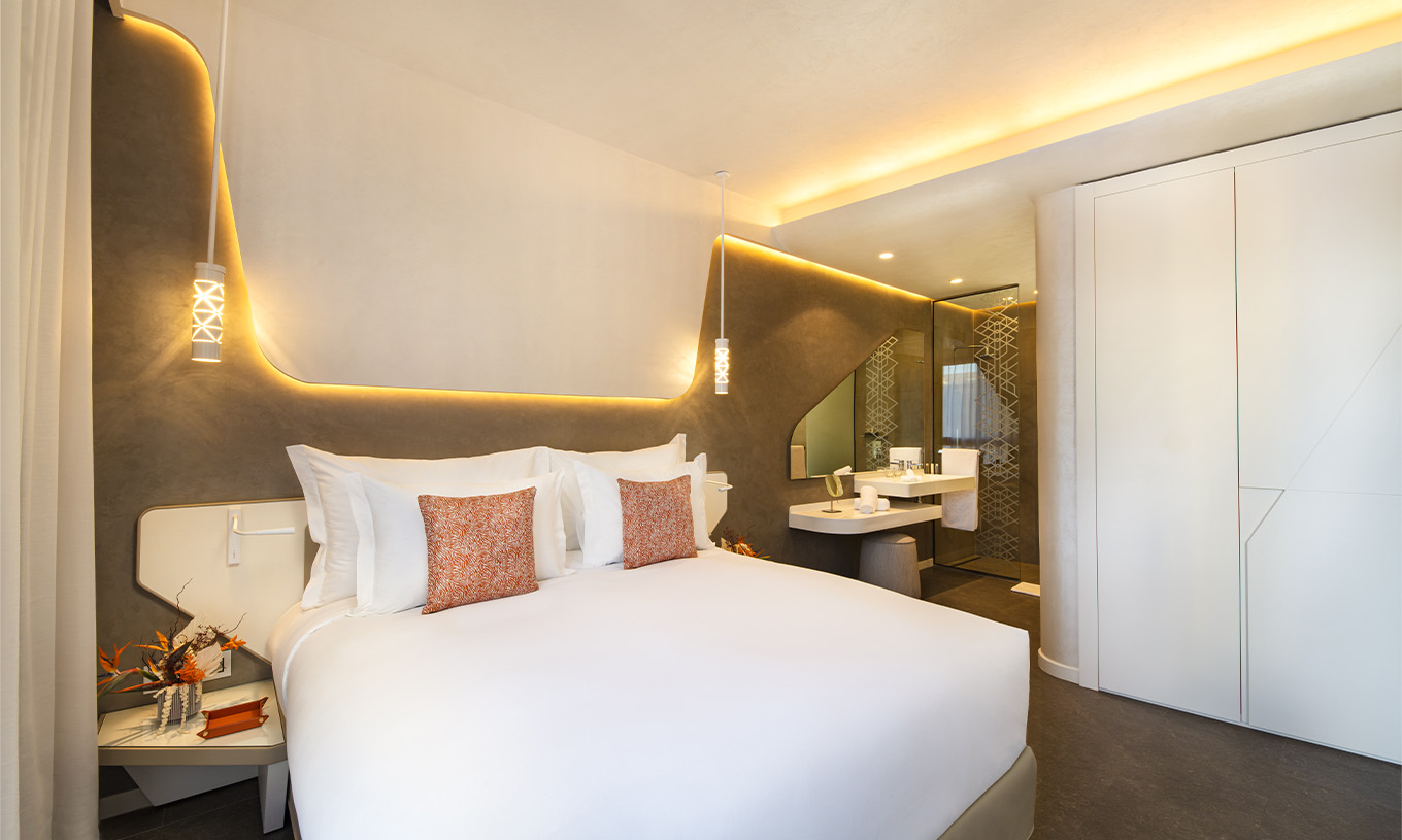 The CR7 Junior Suite at Pestana CR7 Marrakech has a large double bed, wall lights, and a bathroom inside the room