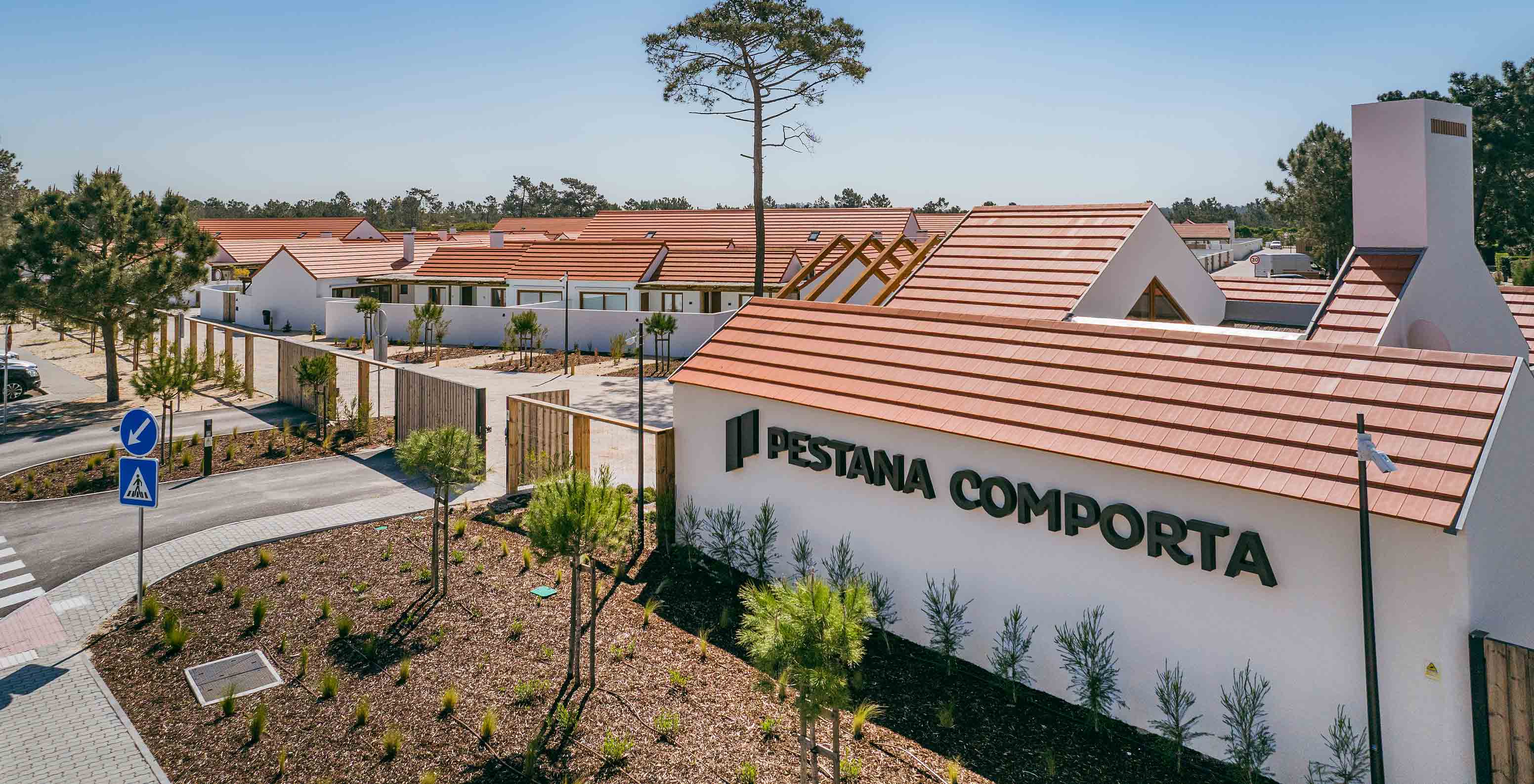 View of Pestana Comporta Village Residences, consisting of villas with red roofs, surrounded by greenery and trees