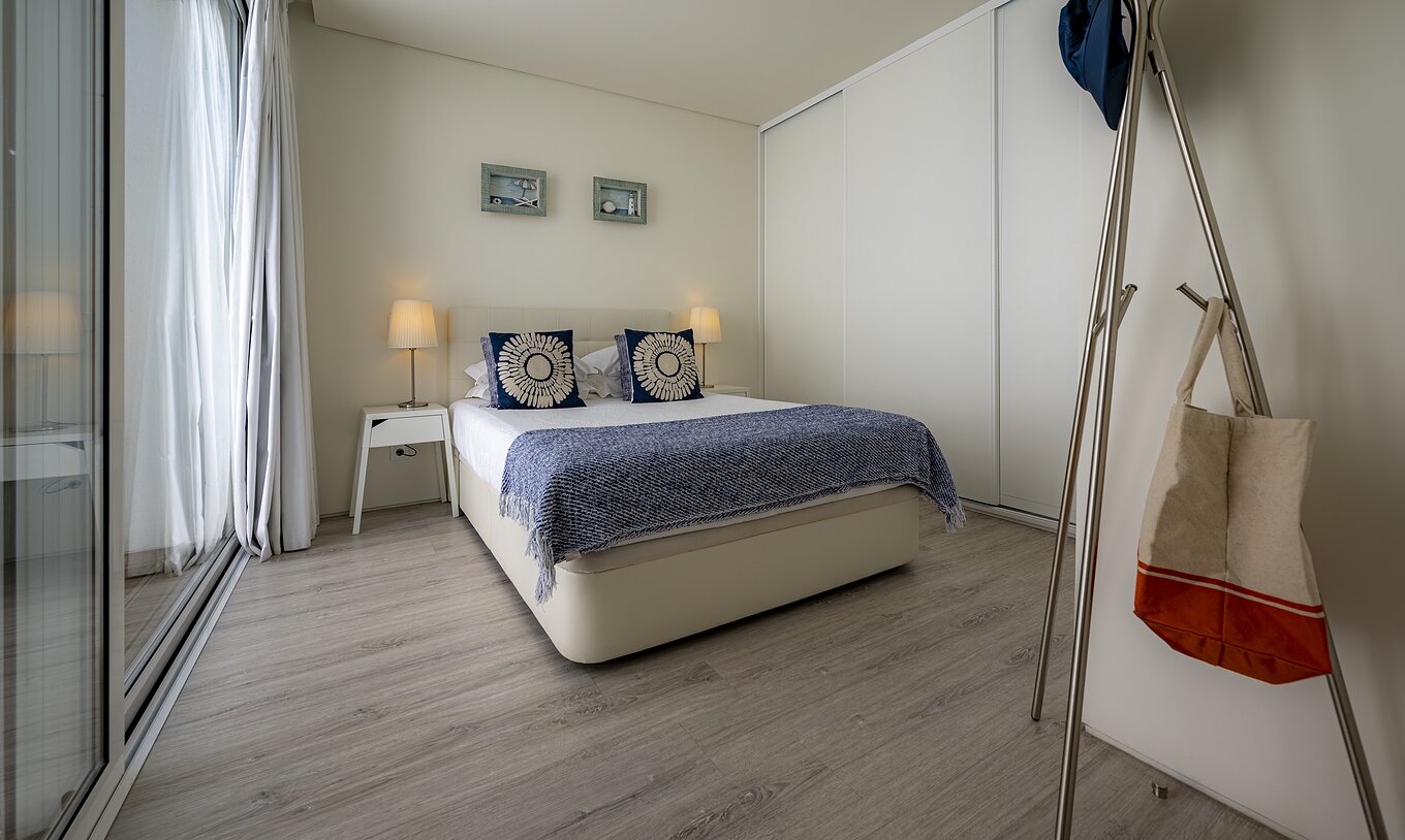 The Green Villa of Pestana Tróia Eco Resort has a double bed with two bedside tables and a blue bedspread