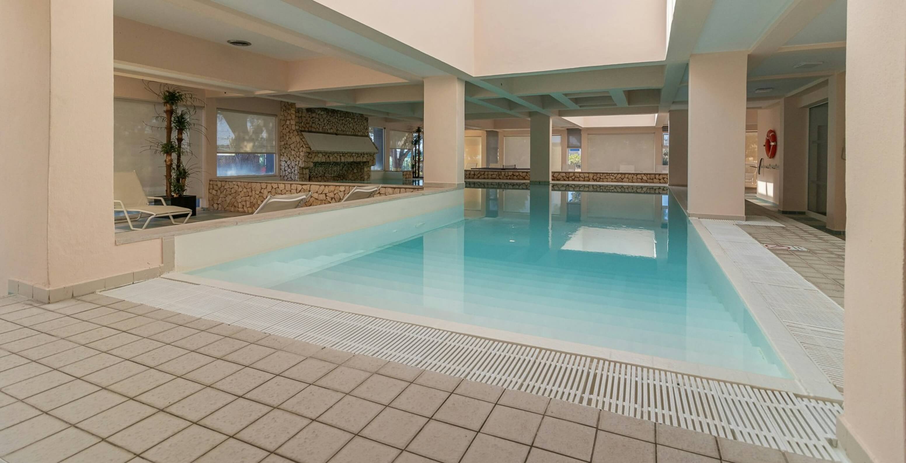 Indoor pool with natural light and loungers in the aparthotel facing the sea