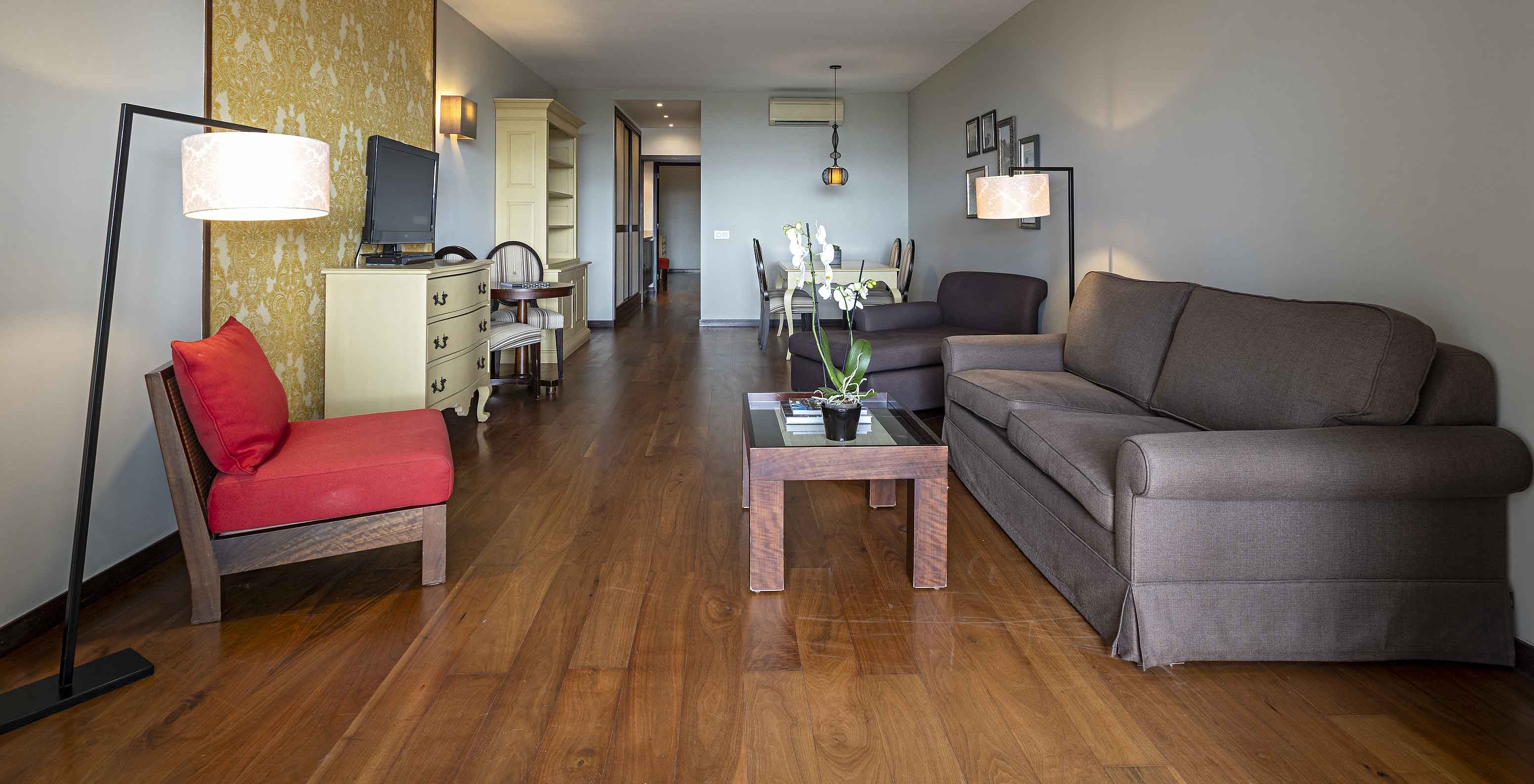 The Cliff Suite T2 at Pestana Alvor Praia has a living room with two sofas, wallpaper, a television, and a table