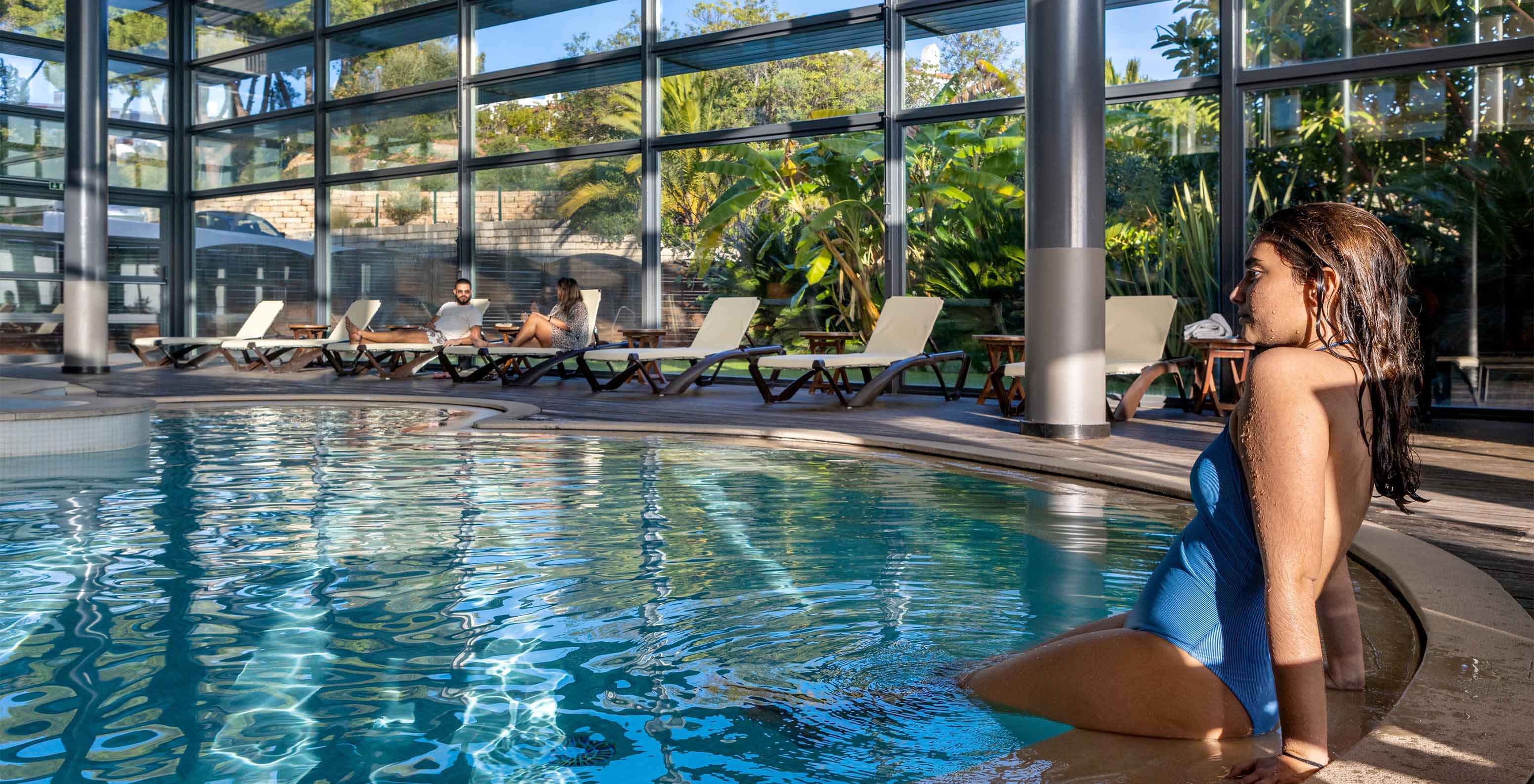 Lady at the edge of the indoor pool with loungers at Pestana Alvor Praia, Hotel with Spa and Pool