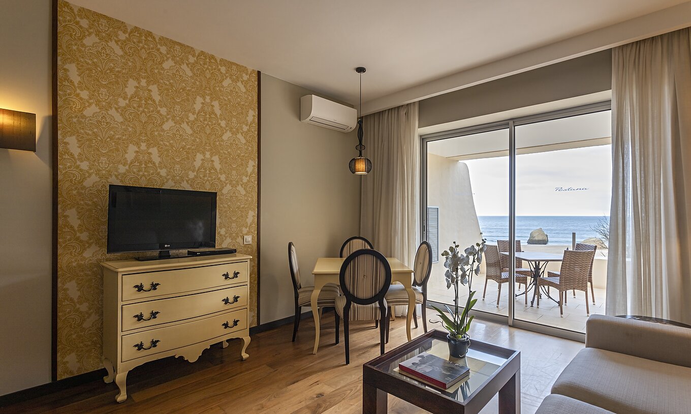 The Cliff Suite T1 at Pestana Alvor Praia has a living room with a TV and a balcony with a table, chairs, and a sea view
